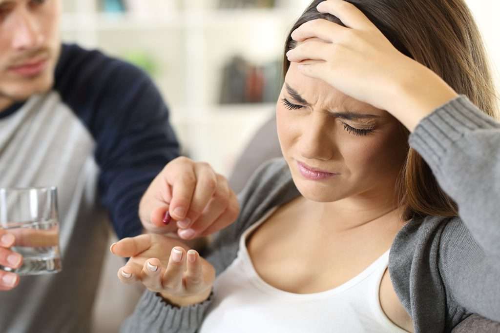 زنی که دچار سردرد شده است و همسرش به وی قرص بهترین سردرد میدهد