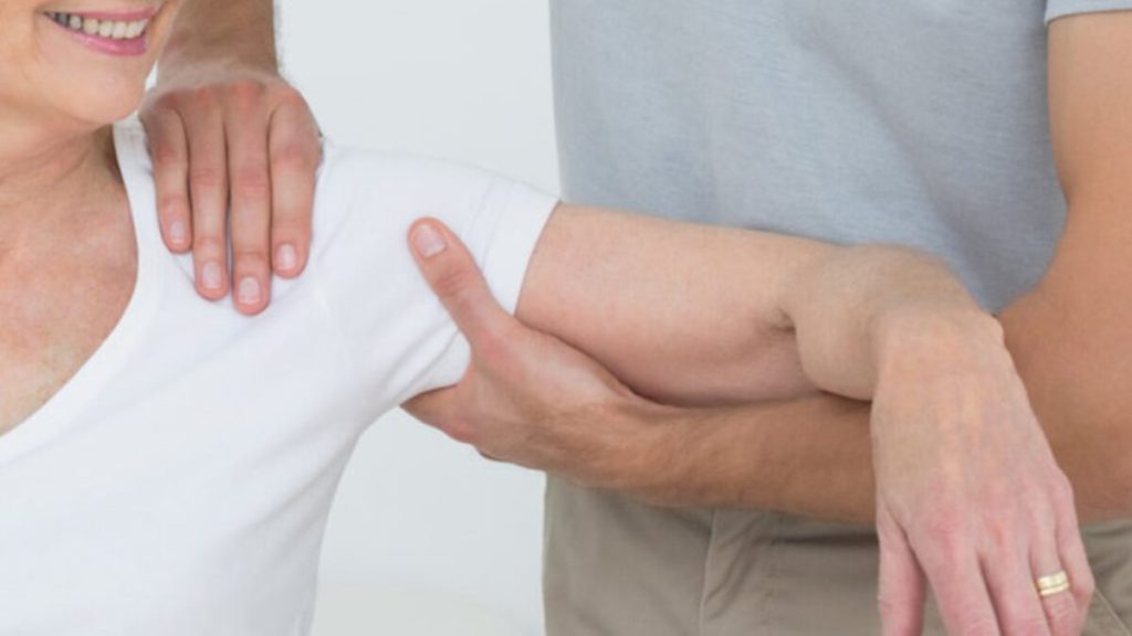 درمان دردهای ناشی از شانه یخ زده با فیزیوتراپی پزشک دست بیمار را گرفته و با حرکات ورزشی به درمان شانه یخ زده کمک می کند